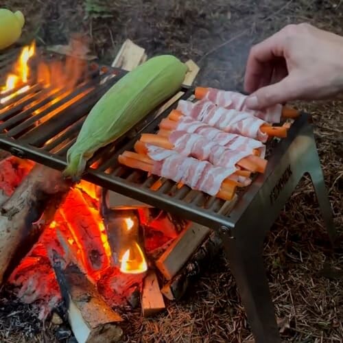 Gemüse und Speck auf einem Grill über Lagerfeuer